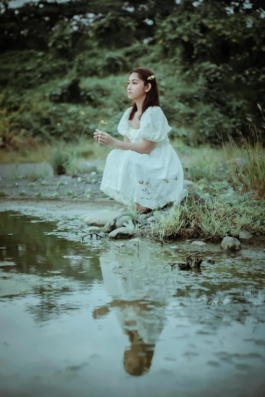 a woman sitting on the bank of a body of water