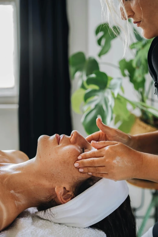 a man getting facial care from a woman sitting in the tub