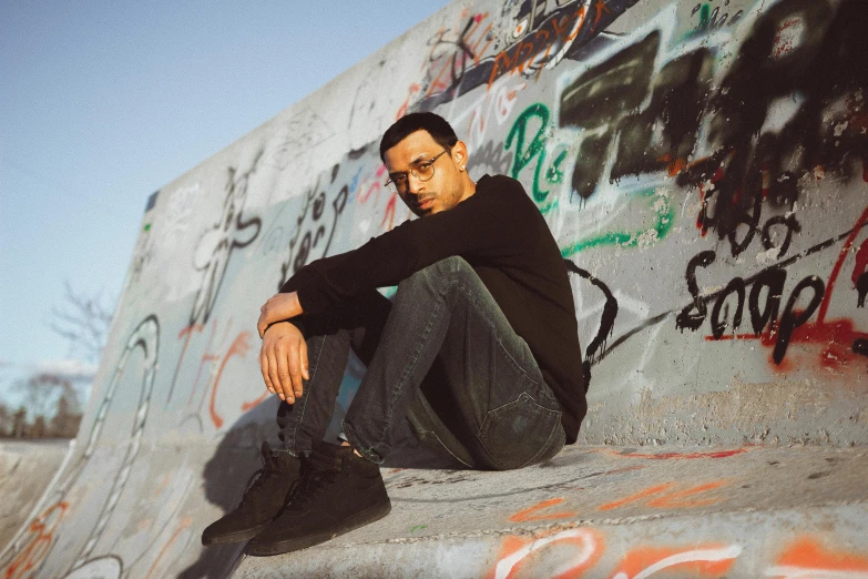 man sitting on ledge next to wall covered in graffiti