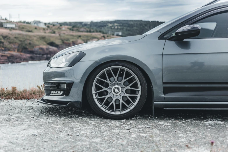 a grey car parked near water on a cloudy day