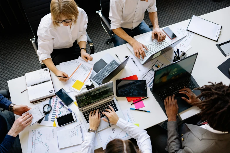 a group of people at a table working on laptops