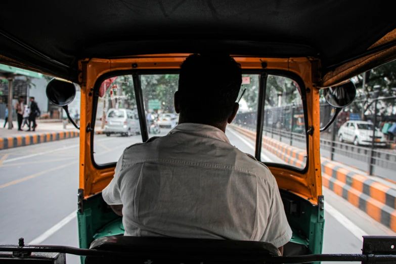 a man in an orange and green truck driving down the road