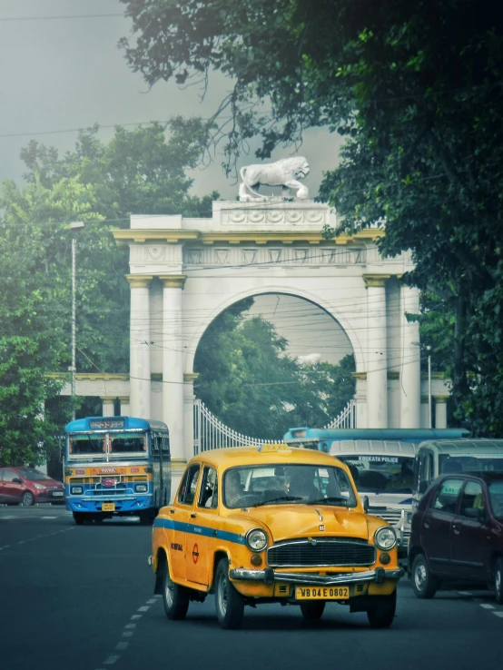 there is an old yellow taxi that is coming down the street