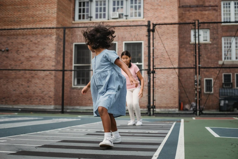 two children are playing with a tennis ball on a court