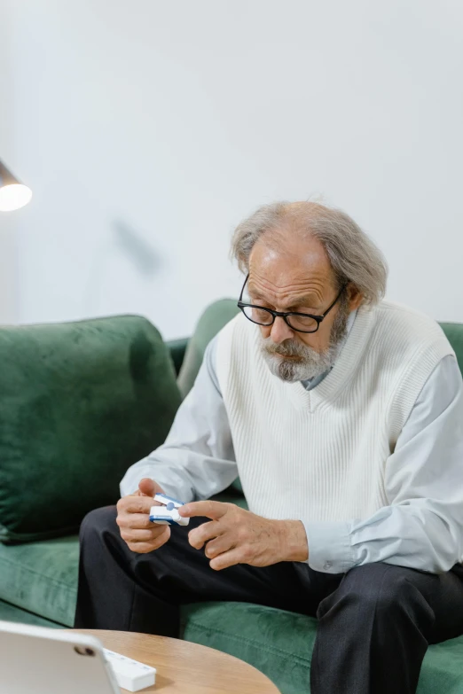 an old man sits on the couch with a smart phone