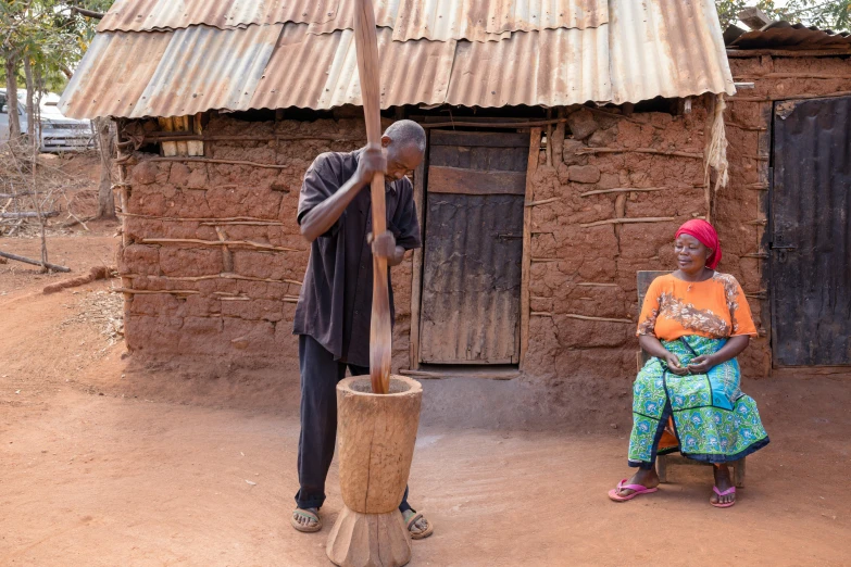 a woman standing next to a man that is holding an umbrella