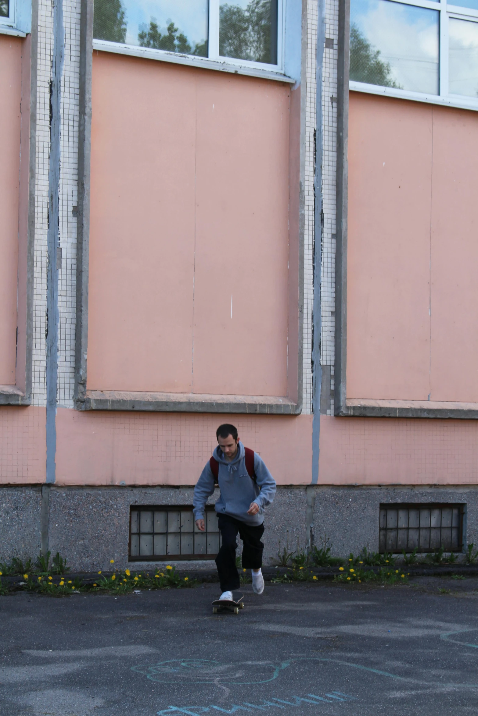 boy on skateboard with arms outstretched and head down against a wall