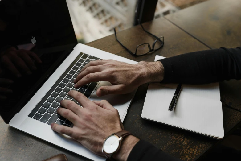 a man sitting at a table typing on his laptop