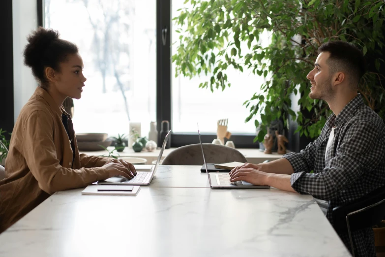 two people sitting at a table with a laptop