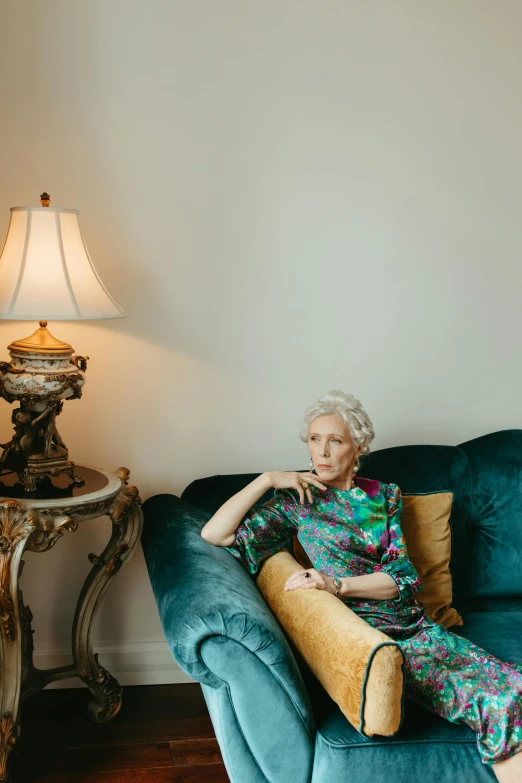 a lady sitting on the couch with her hand on the pillow