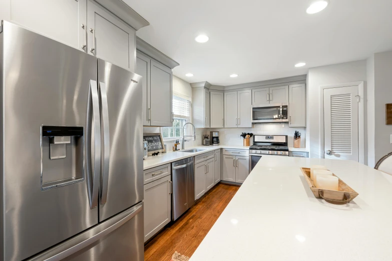 this kitchen has stainless steel appliances, light wood floors and a white counter