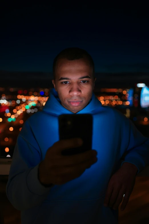 a man holding a phone next to a city at night