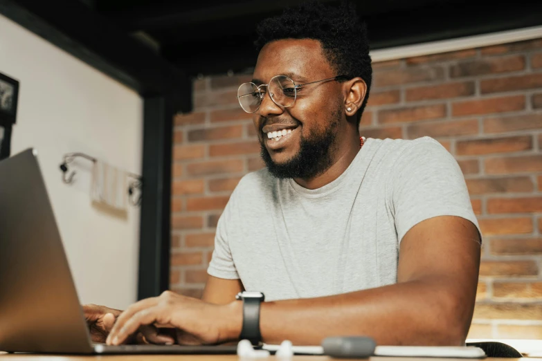 man wearing glasses while using a laptop computer