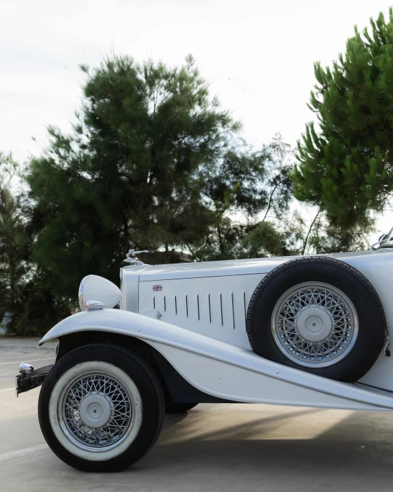 an old car parked in front of some tall trees