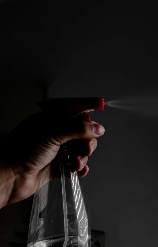 a hand is spraying soap onto a plastic container