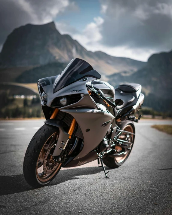 the motorcycle is parked on the road with mountains behind it