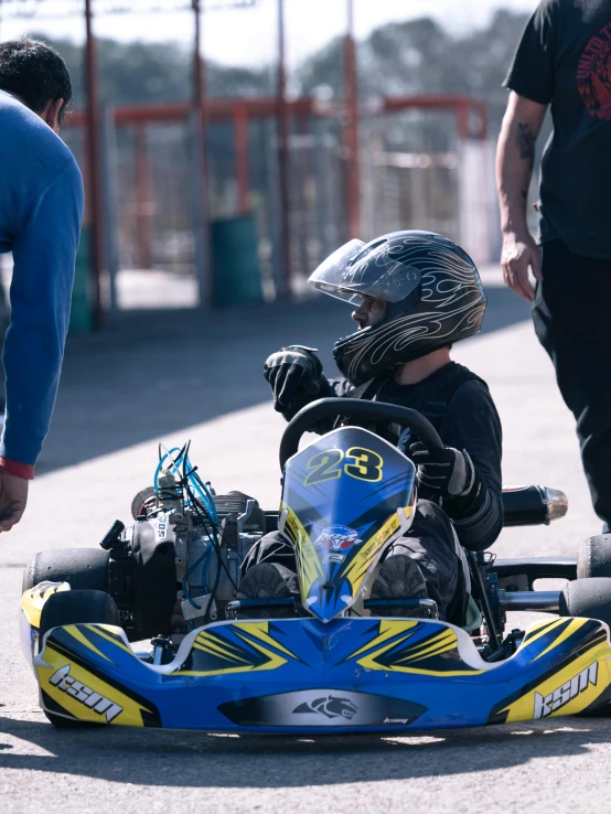 a child wearing a helmet riding a yellow and blue race car