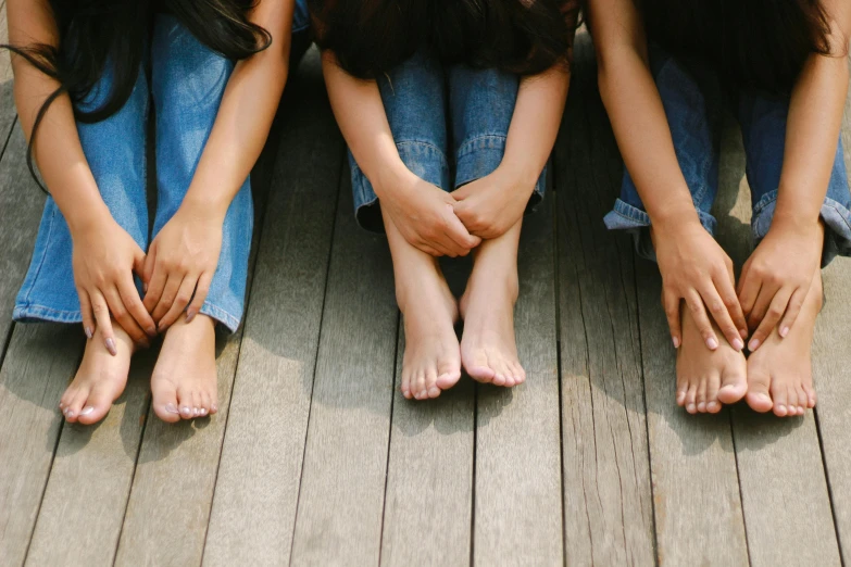 four young women sitting down with their feet propped on each other