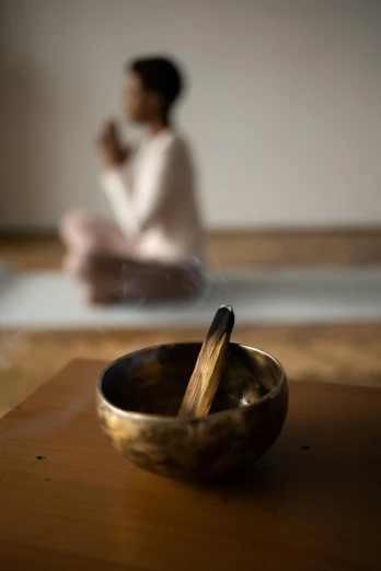 a small bowl sits on a table with a person sitting behind it