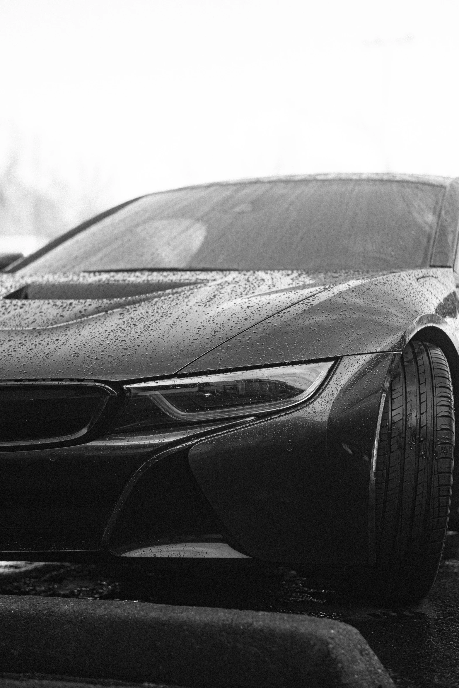 the front of a sports car that is covered in water droplets