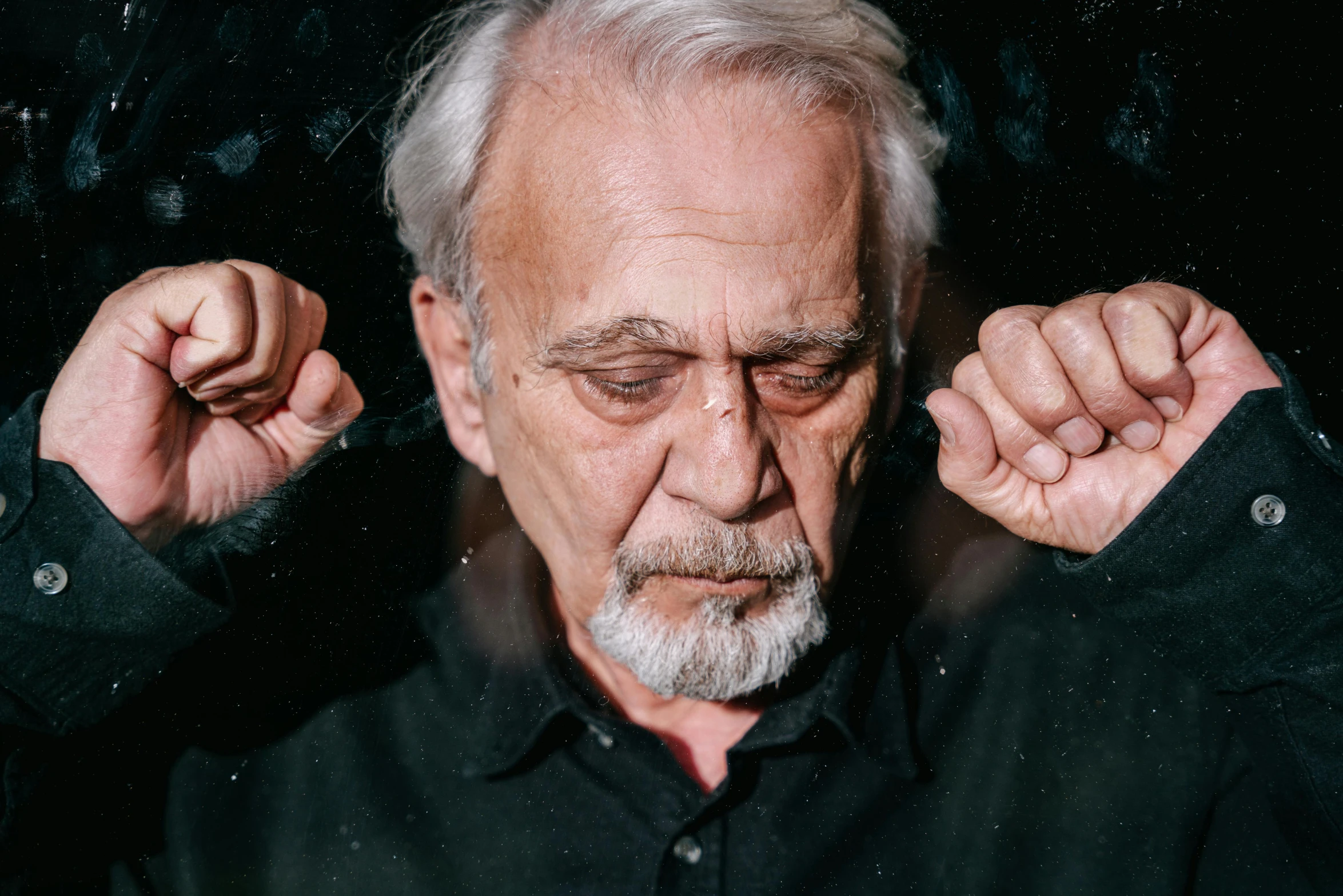 a man with white hair holding his hands up