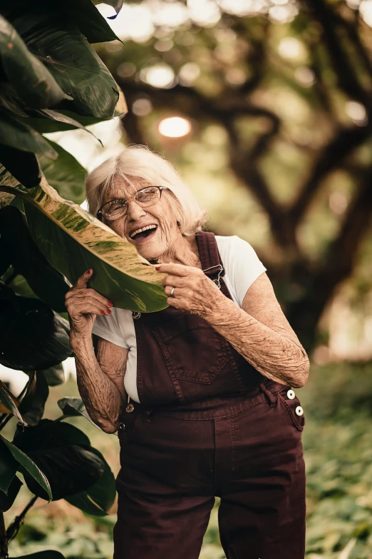 an old woman is standing in front of some plants