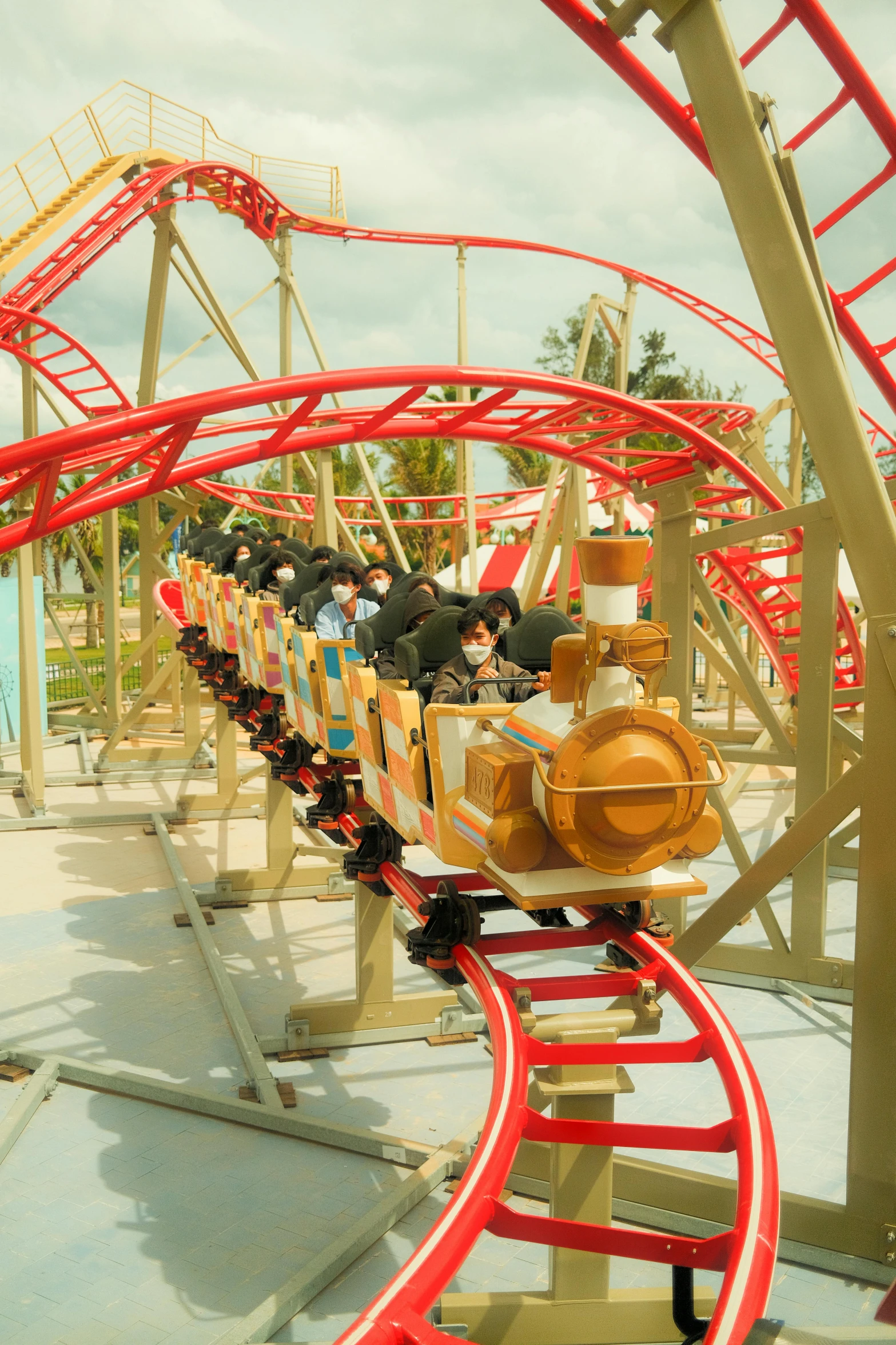 a small orange and red train with a roller coaster going through the air