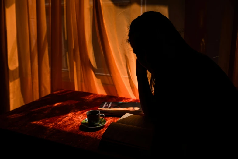 a person sitting at a table in the shadows