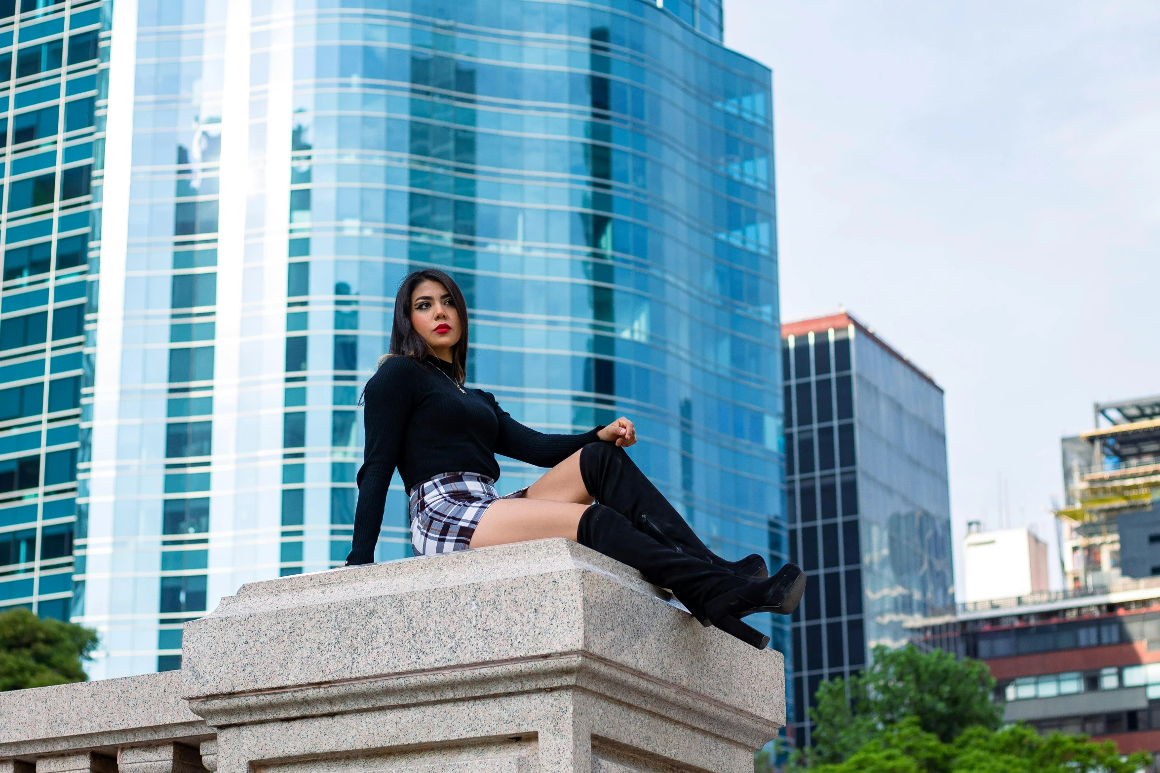 a woman sitting on top of a cement pillar