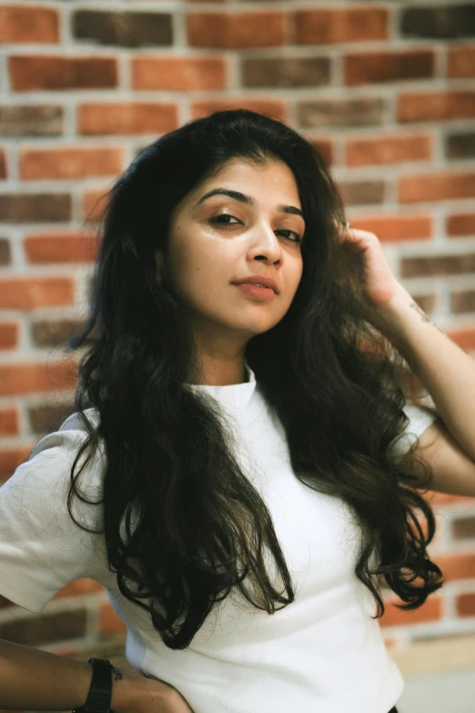 a young woman with long brown hair sitting down wearing a white shirt