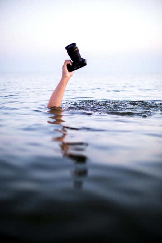 a person holds up a camera in the water