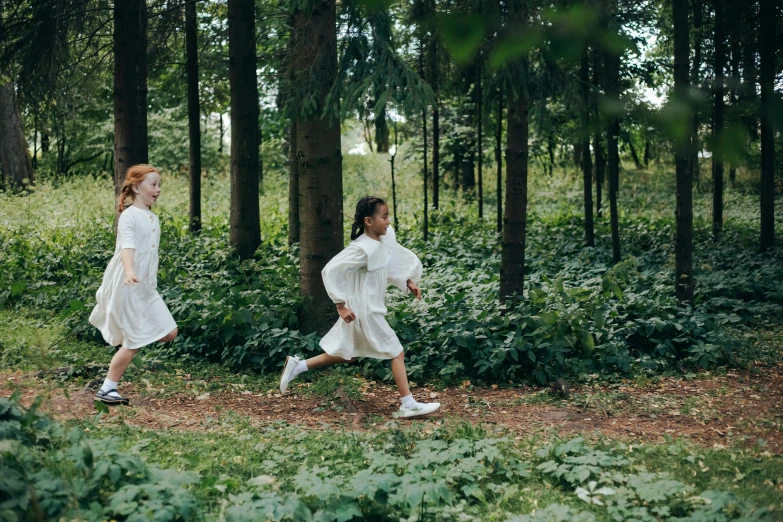 two young children running in the woods during the day