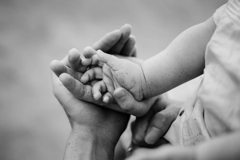 a baby is holding her mother's hands in black and white