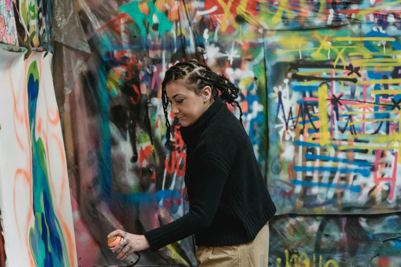 a person with a paintbrush standing in front of graffiti covered wall