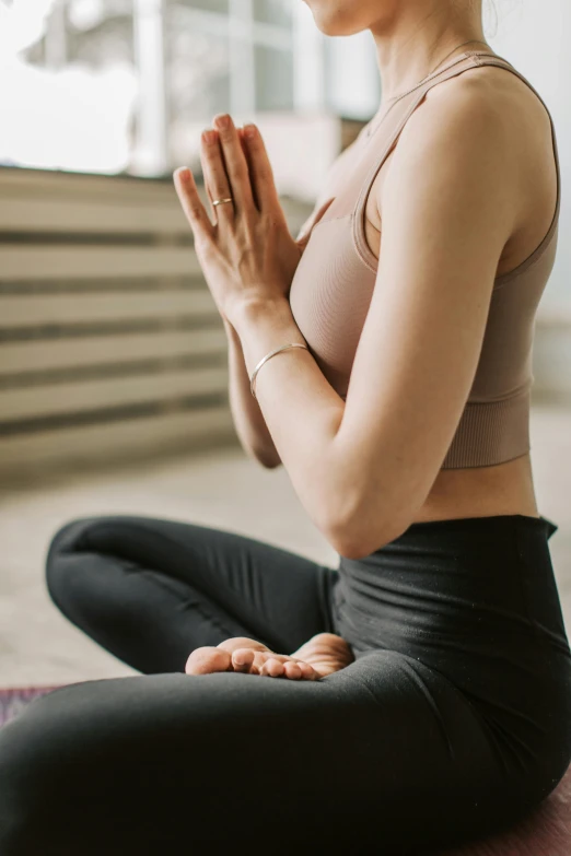 a woman sitting on a floor with her hands clasped