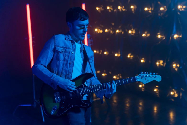 man playing a electric guitar in front of lights