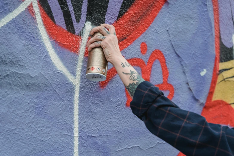 someone spray painting graffiti on the side of a building