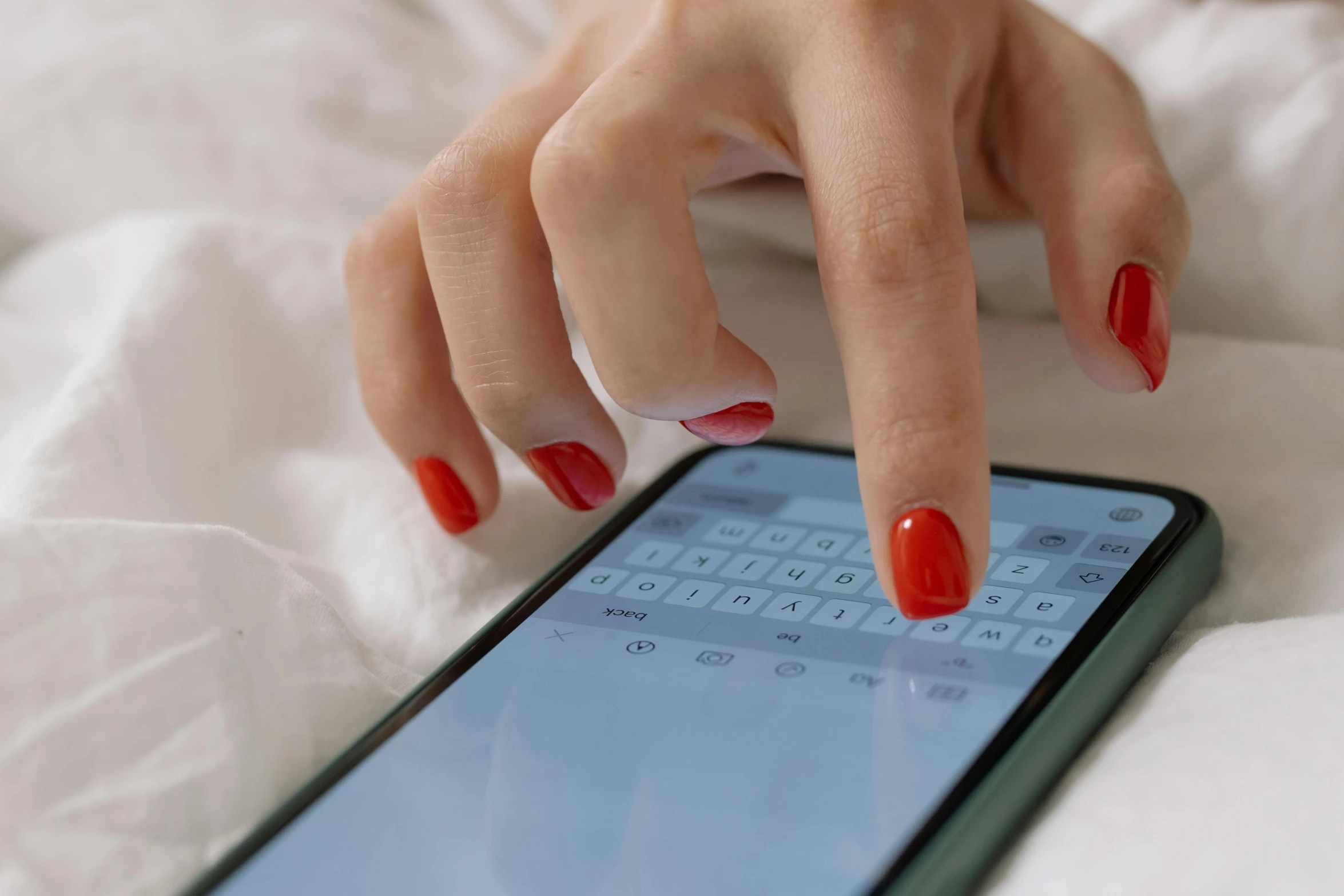 woman with red nail polish taking care of her cell phone