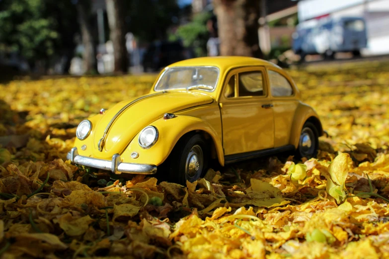 a yellow toy car sitting on top of leaves