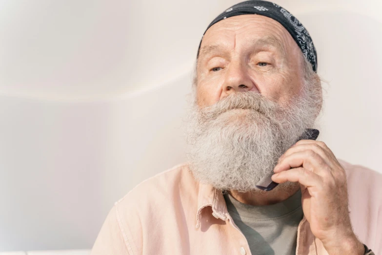 an older man with a grey beard brushing his teeth