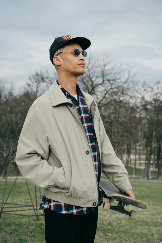 a young man wearing a baseball cap and sunglasses holds a skateboard