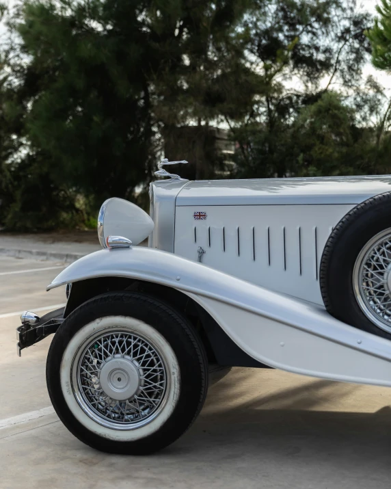 a vintage white car with white tires and spokes