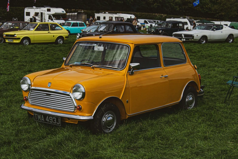 a yellow car in the grass near other cars