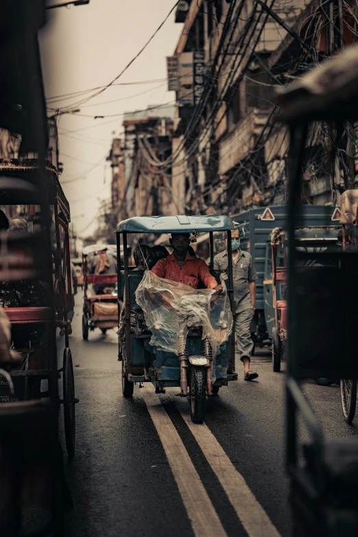 a man driving a small cart in the middle of a busy street