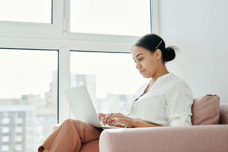 a woman with dark hair on a chair using a computer