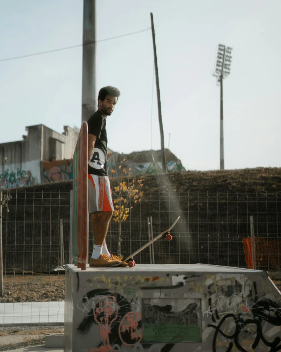 the skateboarder stands on top of the half pipe at a skateboard park