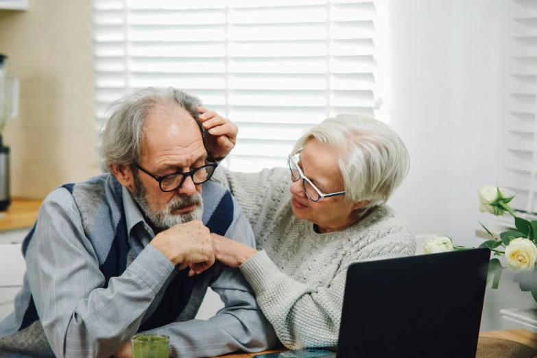 an older couple are looking at a laptop