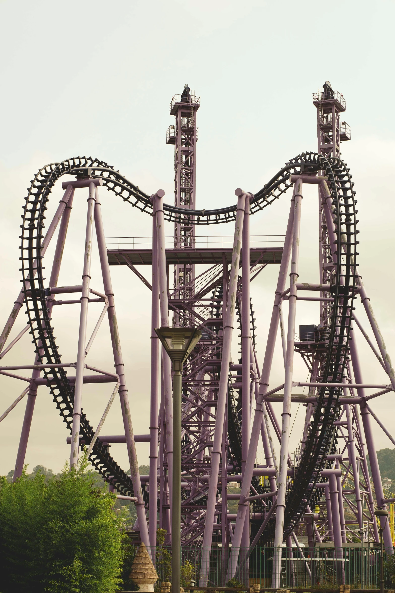 a roller coaster sits atop a hill surrounded by trees