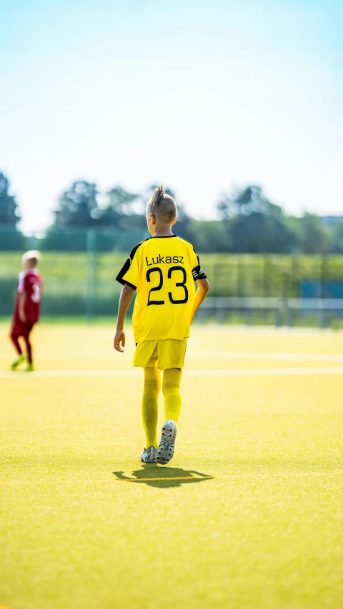 a boy in soccer uniform walking towards the ball