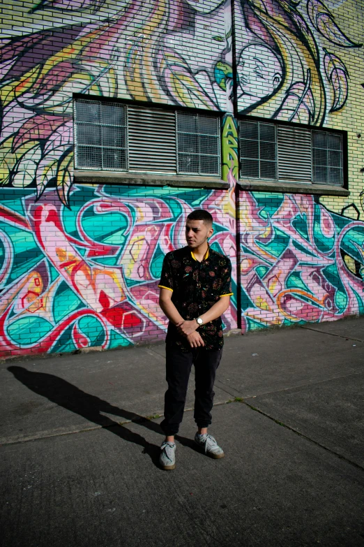 man standing in front of multi colored wall with graffiti